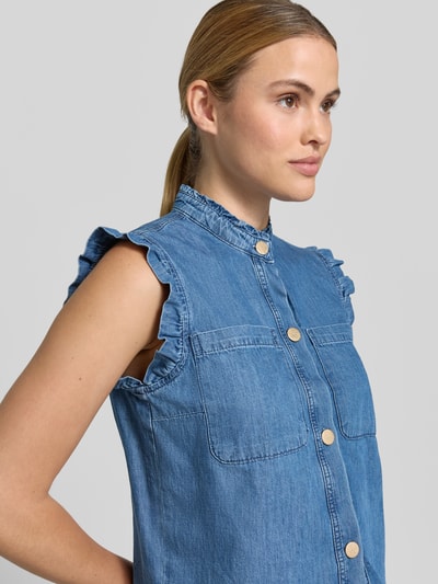 Frauenmodel trägt Regular Fit Hemdbluse in Denim-Optik von More & More aus Reine Baumwolle, Stehkragen mit Rüschenbesatz, Brusttaschen, Ärmelloses Design, durchgehende Knopfleiste, Rückenlänge bei Größe 36: 50 cm, Hellblau mit feiner Oberflächenstruktur, Nahaufnahme Oberkörper.