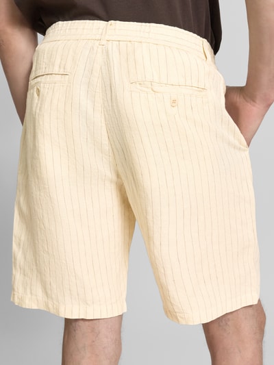 Männermodel trägt Straight Fit Leinenshorts mit Gesäßtaschen von Gant aus Reine Leinen in Beige, feine Streifen, Ganzkörperansicht Rückansicht.