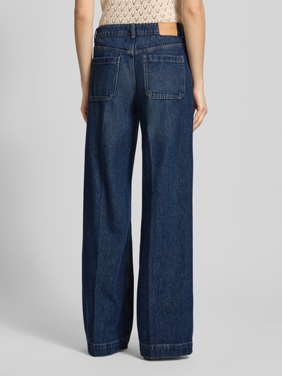 Kobiece model prezentuje Wide Leg Jeans mit aufgesetzten Taschen od Review, ciemnoniebieski denim, czysta bawełna, bügelfalten, szerokość w rozmiarze 27: 38 cm, długość nogawki wewnętrznej w rozmiarze 27: 82 cm, widok całej sylwetki z tyłu.