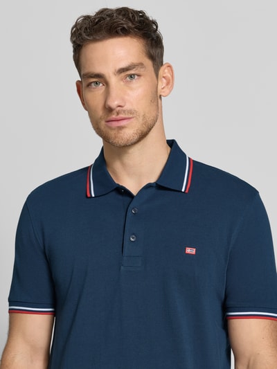 Männermodel trägt Regular Fit Poloshirt mit Kontraststreifen von Christian Berg Men aus reiner Baumwolle, Nahaufnahme Oberkörper.