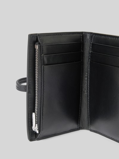 Produktfoto, czarny portfel Portemonnaie mit Schlaufenverschluss Modell 'PEBBLE' od CK Calvin Klein, fakturowany wzór, główna przegroda, przegródka na monety z zamkiem błyskawicznym, przegródki na karty i banknoty, damski portfel