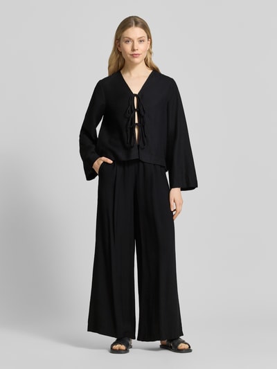 Frauenmodel trägt Wide Fit Stoffhose aus Viskose-Mix Modell 'Frencis' von STEHMANN in Schwarz mit elastischem Bund und Eingrifftaschen, Ganzkörperansicht von vorne.