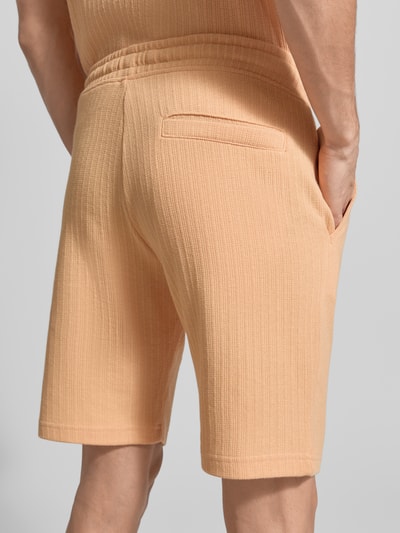 Männermodel trägt Regular Fit Shorts mit Tunnelzug von MCNEAL, Apricot, Baumwoll-Mix mit Stretch-Anteil, Struktur, Ganzkörperansicht Rückansicht.