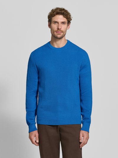 Męski model nosi Regular Fit Strickpullover aus Baumwoll-Mix von MCNEAL, niebieski, okrągły dekolt, elastyczne wykończenia, długość tyłu 65 cm, długość rękawów 56 cm, Ganzkörperansicht von vorne.