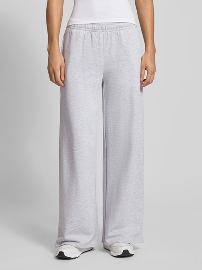 Kobiece model prezentuje Wide Fit Sweatpants mit elastische Bund od Gina Tricot, mieszanka bawełny, krój wide fit, długość wewnętrzna nogawki 76 cm, jasnoszary kolor, struktura gładka, widok z przodu na całe ciało.