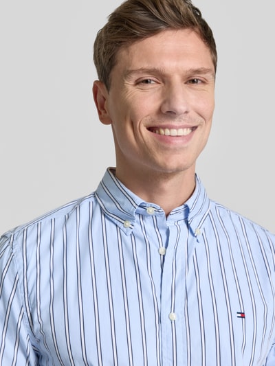Männermodel trägt Regular Fit Freizeithemd aus reiner Baumwolle von Tommy Hilfiger in Hellblau mit dunkelblauen Streifen, Nahaufnahme Oberkörper.