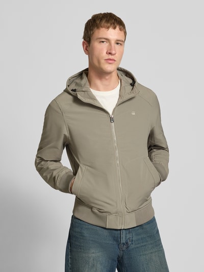Mannenmodel draagt Regular Fit Jacke mit Logo-Print Modell 'Track' van G-Star Raw in beige met capuchon, vooraanzicht bovenlichaam.
