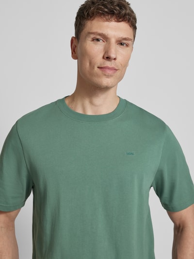 Männermodel trägt T-Shirt mit Label-Stitching Modell 'Bobby' von Wood Wood, reine Baumwolle, gerader Schnitt, Rundhalsausschnitt, Nahaufnahme Oberkörper.