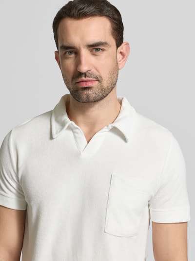 Männermodel trägt Relaxed Fit Poloshirt mit V-Ausschnitt von Lindbergh aus weißem Baumwoll-Mix und Frottee, Brusttasche, Nahaufnahme Oberkörper.