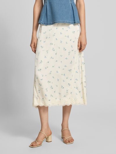 Frauenmodel trägt Ausgestellter Midi-Rock aus reiner Viskose Modell 'SateenSk' von Jake*s Casual, cremefarben mit zarten Blumenmustern, Spitzenbesatz am Saum, Nahaufnahme Unterkörper.