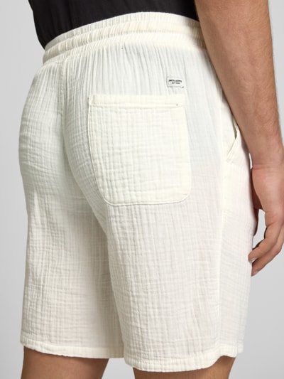 Männermodel trägt Shorts mit Strukturmuster Modell 'AIDEN' von Jack & Jones, cremefarben, elastischer Bund, Detailaufnahme Rückansicht. Material-Mix mit Baumwoll-Anteil, Straight Fit, Bundweite bei Größe M: 40 cm, Innenbeinlänge 21 cm, seitliche Eingrifftaschen, mit Label-Patch.