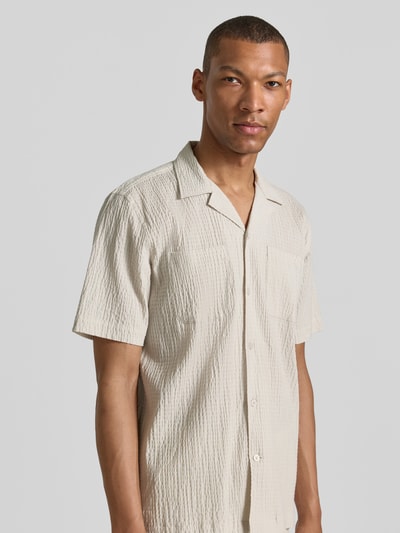 Männermodel trägt Modern Fit Freizeithemd mit Brusttaschen von Lindbergh aus Baumwoll-Mix mit Stretch-Anteil, Strukturmuster, Reverskragen, Knopfleiste; sanfte Beige-Töne, lockere Textur, Nahaufnahme Oberkörper.