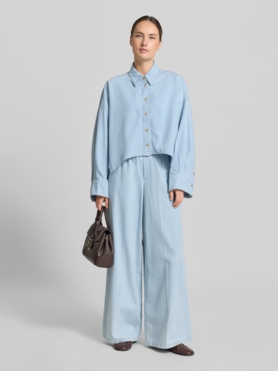 Modelka nosi Wide Fit Stoffhose in Denim-Optik Modell 'Ceiling' od Drykorn z czystej bawełny, szerokość w rozmiarze 27/34: 36 cm, długość wewnętrzna nogawki: 79 cm, elastyczny pas, wygląd jeansu, jasnoniebieski kolor, widok całej sylwetki z przodu.