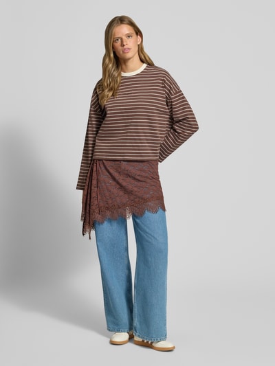 Vrouwenmodel draagt minirok uit elastische materiaalmix met asymmetrische look en met kant, semi-transparante look, totale lengte maat 1: 40 cm, Model 'Phelia' van OH APRIL, voorkant volledige lichaamsopname.