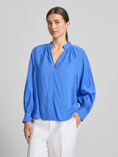 Frauenmodel trägt Bluse aus Viskose-Mix mit Serafino-Ausschnitt von Christian Berg Woman in Blau, lockere Passform, Sportmanschetten, Nahaufnahme Oberkörper.
