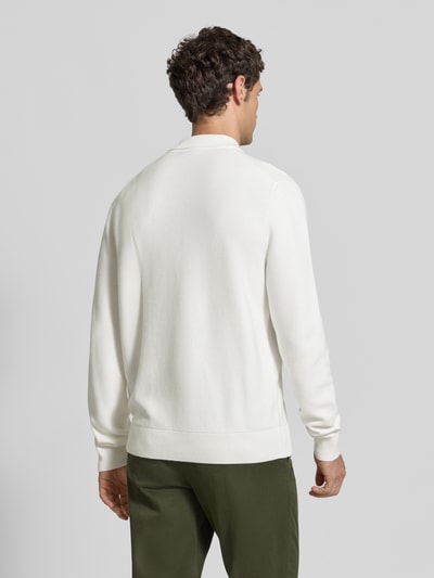 Männermodel trägt Regular Fit Poloshirt aus reiner Baumwolle von Lacoste in Weiß, kombiniert mit grüner Hose, Ganzkörperansicht Rückansicht. Herren Poloshirt von Lacoste.