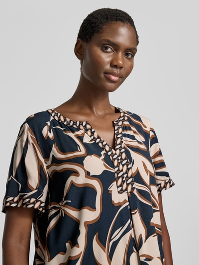 Frauenmodel trägt A-Linien Freizeitkleid aus reiner Viskose von Betty Barclay mit großem Blumenmuster in Beige, Braun und Dunkelblau, Nahaufnahme Oberkörper.