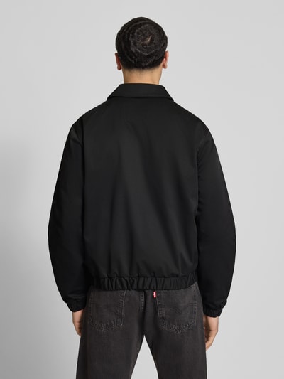 Männermodel trägt schwarze Herren Jacke mit Umlegekragen, Zweiwege-Reißverschluss, Label-Stitching, Modell 'CATSKILLS' von Jack & Jones, Regular-Fit, Rückenlänge 64 cm, Schulterbreite 49 cm, Brustweite 59 cm, Ärmellänge 66 cm, Ganzkörperansicht Rückansicht.