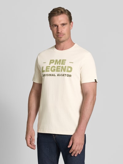 Mannenmodel draagt T-shirt met ronde hals en labelprint van PME Legend in offwhite, puur katoen, regular fit, ruglengte maat M 64 cm. Ganzlichaansicht van voren.