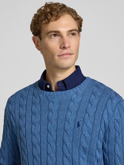 Männermodel trägt Regular Fit Pullover aus reiner Baumwolle von Polo Ralph Lauren in Blau mit Zopfmuster-Struktur, Nahaufnahme Oberkörper.
