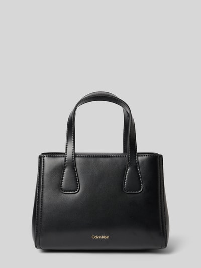 Produktfoto, Torebka 'Handtasche mit Label-Applikation' od CK Calvin Klein, czarna, prostokątna forma, gładka tekstura, główna przegroda z zapięciem na magnes, aplikacja z metką, uchwyt, odpinany pasek na ramię, szerokość w rozmiarze 1: 18 cm, długość w rozmiarze 1: 14 cm, głębokość w rozmiarze 1: 9 cm, długość paska na ramię w rozmiarze 1: 108 cm