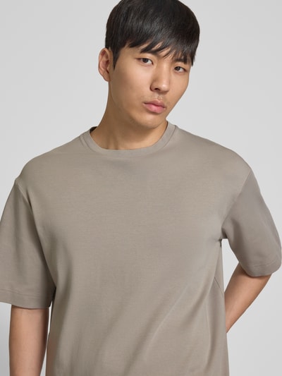 Männermodel trägt T-Shirt mit Logo-Print und Rundhalsausschnitt von Profuomo in Beige, Bio-Baumwolle, Relaxed-Fit, Nahaufnahme Oberkörper.