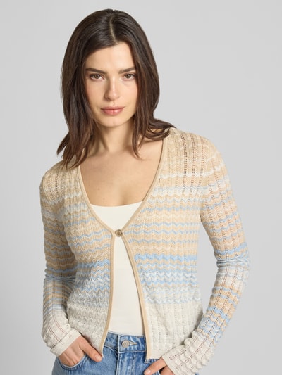 Modelka kobieca ma na sobie Strickjacke aus Viskose-Mix Modell 'ROSALYN' od Guess, beżowo-niebieskie odcienie, wzór w paski, damska, krój prosty, V-dekolt, zapięcie na guzik, długość tyłu 51 cm, długość rękawa 69 cm, widok na górną część sylwetki z przodu.