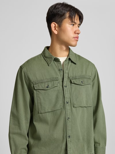 Männermodel trägt Loose Fit Jeanshemd aus reiner Baumwolle von Levi's® in Olivgrün, Struktur fein, Nahaufnahme Oberkörper.