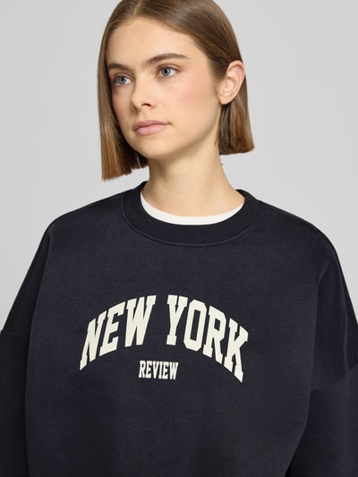 Vrouwenmodel draagt Sweatshirt met Labelprint en ronde hals van Review in donkerblauw, katoenmix, relaxed fit, nahaufnahme bovenlichaam.