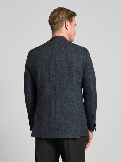 Männermodel trägt Slim Fit Sakko mit Viskose-Anteil Modell 'Theo' von Carl Gross in dunkelgrau, dezente Struktur, Ganzkörperansicht Rückansicht. Material-Mix, Reverskragen, Brust- und Pattentaschen.