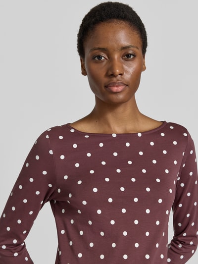 Frauenmodel trägt Shirt aus reiner Baumwolle mit 3/4-Arm von Christian Berg Woman, taillierte Passform, U-Boot-Ausschnitt, braun mit weißen Punkten, Nahaufnahme Oberkörper.