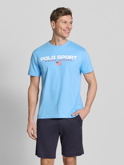 Männermodel trägt Relaxed Fit T-Shirt aus reiner Baumwolle von Polo Ralph Lauren, unifarbenes Hellblau mit Label Print, Rundhals, Kurzarm, Ganzkörperansicht von vorne.