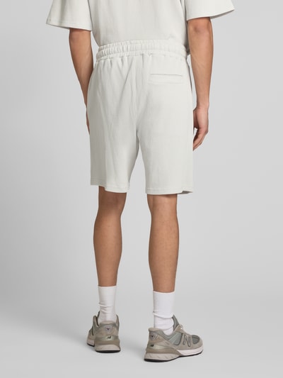 Männermodel trägt Shorts mit Logo-Stitching und elastischem Bund von Pegador in Weiß, Reine Baumwolle, Loose-Fit, Feinripp, Gesäßtasche, Ganzkörperansicht Rückansicht.