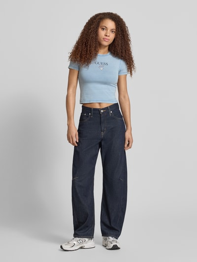 Frauenmodel trägt Cropped Damen T-Shirt von Guess Jeans, Baumwoll-Elasthan-Mix, Modell 'BABY BAKER TEE', Logo, Rundhalsausschnitt, Ganzkörperansicht von vorne.