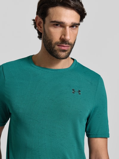 Männermodel trägt Slim Fit T-Shirt mit Logo-Print Modell 'Vanish' von Under Armour in Türkis mit Lochmuster, Nahaufnahme Oberkörper.