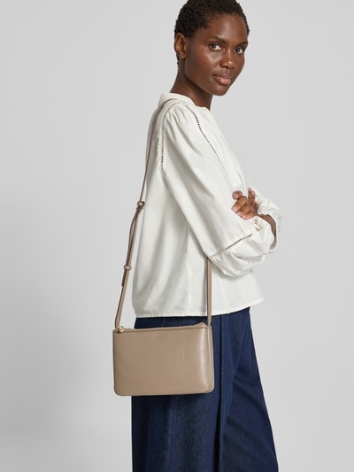 Frauenmodel trägt Umhängetasche aus echtem Leder von BOSS in Beige, glatte Oberfläche, lockere Kleidung, Ganzkörperansicht von vorne. Damen Umhängetasche von BOSS.