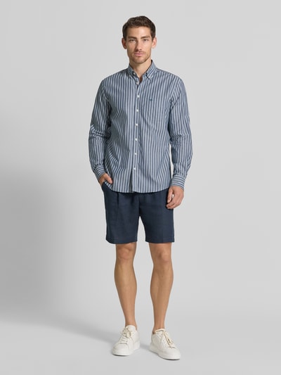Männermodel trägt blauw-wit gestreept slim fit vrijetijdsoverhemd met button-downkraag, borstzak en labelstitching van Fynch-Hatton, puur katoen, all-over look, ruglengte maat M 80 cm, schouderbreedte 52 cm, mouwlengte 68 cm, geheel vooraanzicht
