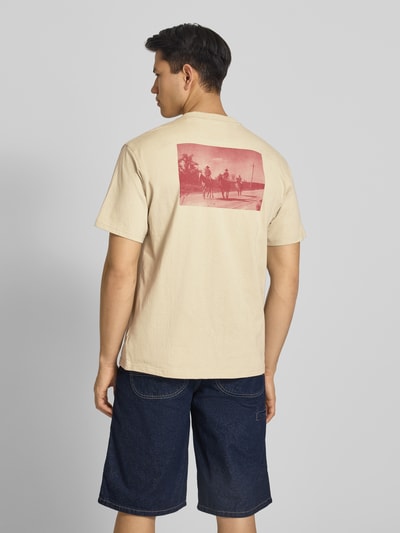Männermodel trägt Herren T-Shirt mit Logo Modell 'MILLVILLE' von Dickies in Beige, Reine Baumwolle, Relaxed-Fit, Rückenlänge 70 cm, Ganzkörperansicht Rückansicht.