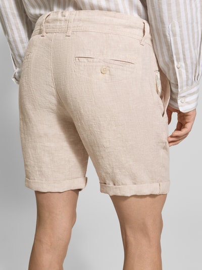 Mężczyzna nosi Leinenshorts mit Bindegürtel und Gesäßtaschen von MCNEAL, len, krój straight fit, wiązany pasek, wpuszczane kieszenie, zakładka, szerokość w rozmiarze M: 45 cm, długość wewnętrzna nogawki w rozmiarze M: 16 cm, wyhaftowane logo, kolor jasnobeżowy, tekstura lnu, widok całej sylwetki z tyłu.
