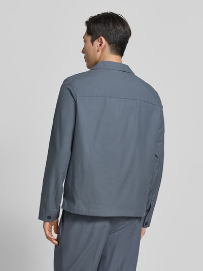 Männermodel trägt Oversized Hemdjacke aus Baumwoll-Lyocell-Mix von CK Calvin Klein, jednolity kolor, tkanina twill, długie rękawy, widok całej sylwetki z tyłu.