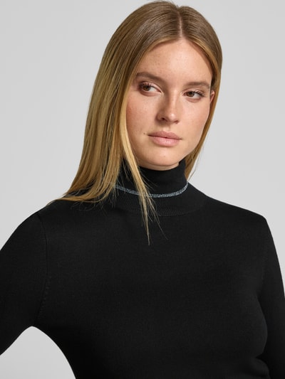 Frauenmodel trägt Slim Fit Longsleeve aus Viskose-Mix Modell 'MAGLIA CHIUSA' von Liu Jo White in Schwarz mit Stehkragen und Logo-Detail, Nahaufnahme Oberkörper. Damen Longsleeve, Rückenlänge 57 cm, Ärmellänge 66 cm.