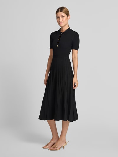 Frauenmodel trägt Polokleid aus Viskose-Mix mit Knopfleiste von MICHAEL Michael Kors in Schwarz, Ripp-Optik, A-Linie, Midikleid, Ganzkörperansicht von vorne.