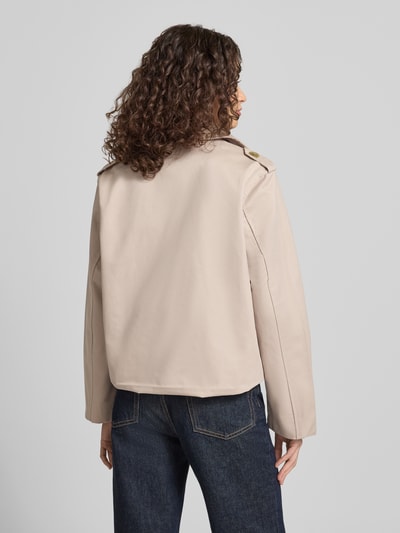 Männermodel trägt Regular Fit Trenchcoat mit Umlegekragen von Review, beżowa bawełna, dwurzędowy, kieszenie, długość tyłu 55 cm, szerokość ramion 45 cm, szerokość klatki piersiowej 53 cm, długość rękawa 62 cm, krój regular fit, widok całej sylwetki z tyłu.