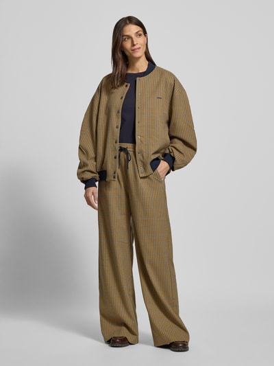 Frauenmodel trägt Loose Fit Bomberjacke mit Knopfleiste Modell 'chicca' von Gestuz in beige-blau kariert mit Stehkragen, Ganzkörperansicht von vorne.