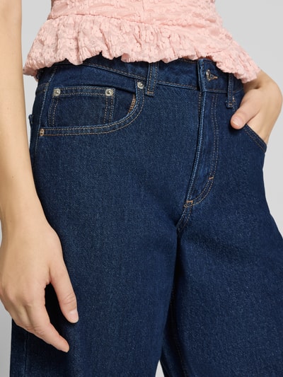 Vrouwenmodel draagt Barrel Jeans im 5-Pocket-Design van Topshop in donkerblauw, puur katoen, knoop- en ritssluiting, detailopname. Bandwijdte bij maat 27/32: 38 cm, binnenbeenlengte bij maat 27/32: 78 cm.