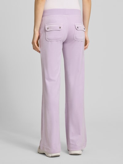 Vrouwenmodel draagt Low Rise Sweatpants met steekzakken model 'LAYLA' van Juicy Couture, materiaalmix met stretch, elastische band, lila tint, binnenbeenlengte maat S: 82 cm, achteraanzicht volledige lichaamsopname.
