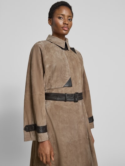 Frauenmodel trägt Ledermantel mit Gürtel und Ärmelriegeln von Emporio Armani in Beige und Schwarz, Relaxed Fit, Nahaufnahme Oberkörper.