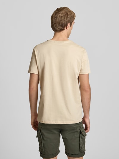 Männermodel trägt T-Shirt mit Logo und Rundhalsausschnitt von Alpha Industries, Reine Baumwolle, Regular-Fit, einfarbig, Rückenlänge 67 cm, Ganzkörperansicht Rückansicht.