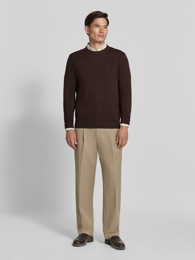 Männermodel trägt Regular Fit Pullover aus reiner Baumwolle von Tom Tailor in Dunkelbraun, beige Hose, Ganzkörperansicht von vorne. Herren Pullover von Tom Tailor