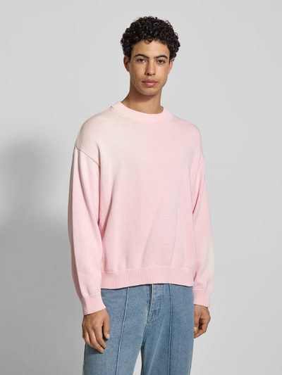 Männermodel trägt Strickpullover mit gerippten Abschlüssen von ANOTHER COTTON LAB in zartem Rosa, Reine Baumwolle, Lockerer Schnitt, Rundhalsausschnitt, Ganzkörperansicht von vorne.